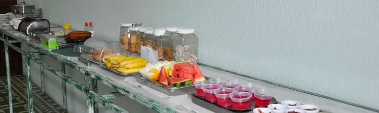 Buffet de café da manhã com frutas, pães e sucos sobre a mesa